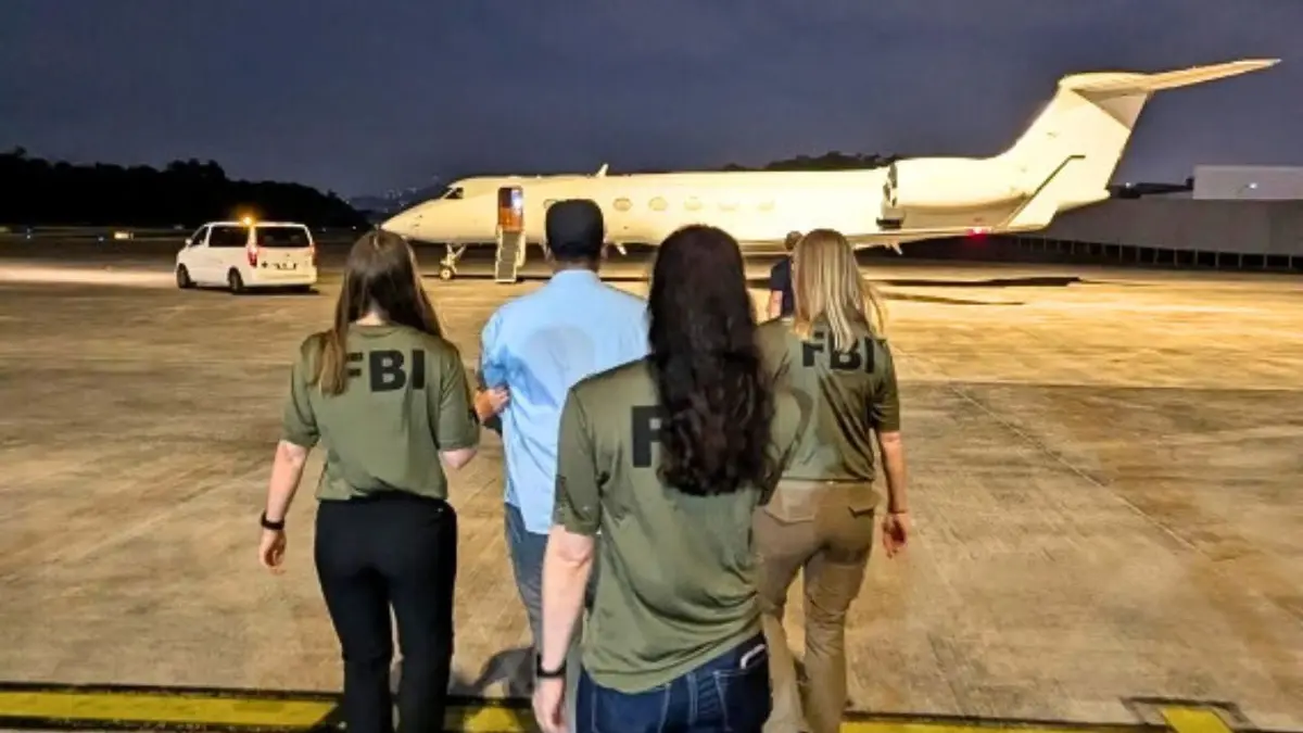 Des agents du FBI escortent un homme sur le tarmac d'un aéroport vers un jet privé pendant son extradition.